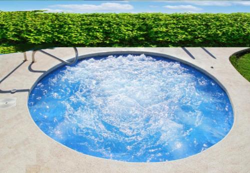 a circular pool of blue water in front of a hedge at Sky House by the Bentota Beach in Bentota
