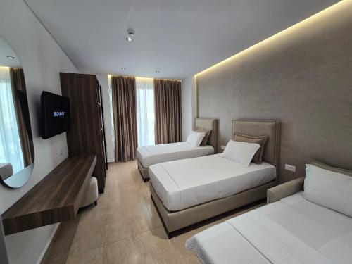 a hotel room with two beds and a television at Sunlight Hotel in Ksamil