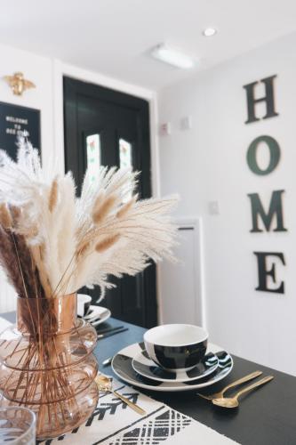 a table with a vase of feathers and a cup at Bee Stays - Long Lane in Warrington