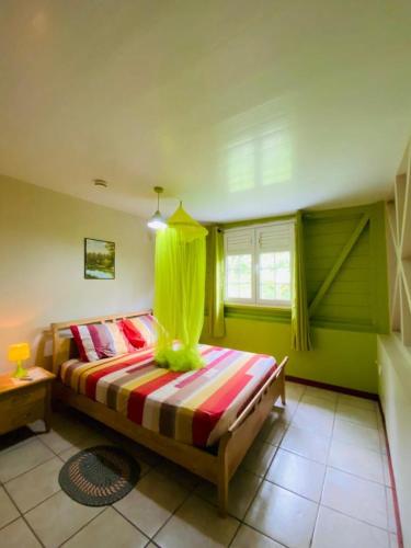 una camera da letto con un letto in una stanza con pareti verdi di Le sucrier a Le Marin