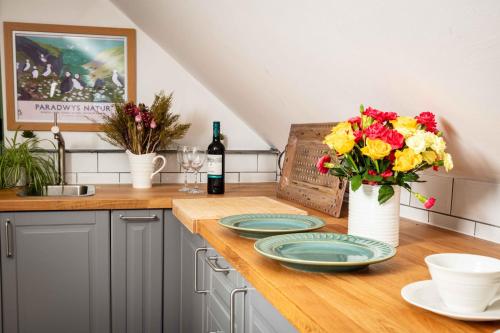 a kitchen counter with plates and flowers in a vase at Cwtch Lackerlee in Haverfordwest
