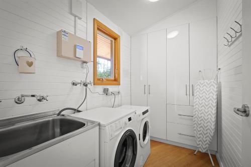 a white laundry room with a sink and a washing machine at Blissful Birchs Bay - Gorgeous 3 Bedroom House in Woodbridge