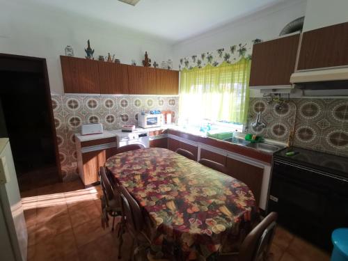 a kitchen with a table and a stove and a sink at Moradia Coelho in Lousã