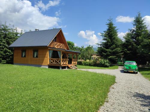 uma pequena cabana de madeira com um camião verde estacionado ao lado em Smrekowa Chatka w Milówce em Milówka