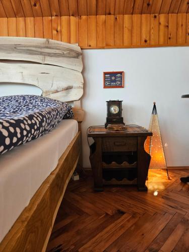 1 dormitorio con 1 cama y 1 mesa con reloj en Drinska Dedovina en Gornja Trešnjica