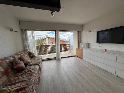 een woonkamer met een bank en een flatscreen-tv bij L'ALPE D'HUEZ Appartement 4 couchages idéalement situé in Huez