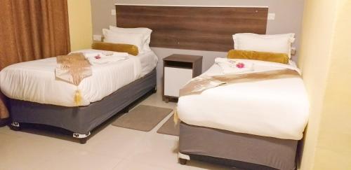 a hotel room with two beds in a room at Etang Guesthouse in Nata