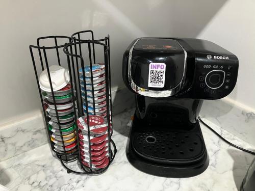 a black coffee maker on a counter with a stack of cups at Lancing Apartments - Spacious 2 Bed - Sleeps 6 - Burnham Village in Slough