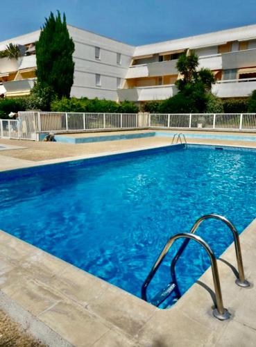 une grande piscine bleue devant un immeuble dans l'établissement Appartement centre ville - Accès piscine - 300M de la plage, à La Grande Motte