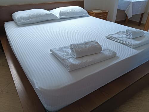 een wit bed met twee handdoeken erop bij Seaside Deluxe Apartment in Durrës