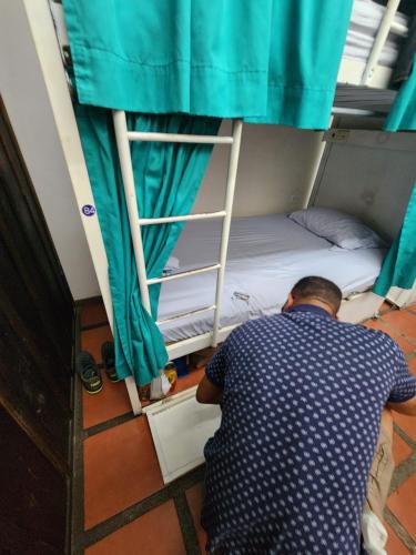 a man sitting in front of a bunk bed at Costa Rica Backpackers in San José