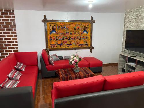 a living room with red couches and a tv at Casa Hospedaje “YURAQ WASI” in Huaraz