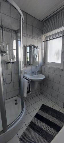 a white bathroom with a shower and a sink at Helle Ferienwohnung mit Garten und Terrasse, direkt am Waldrand gelegen in Herzogenrath
