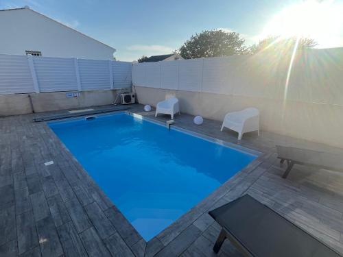 une grande piscine avec deux chaises et une table dans l'établissement Villa avec piscine, à Saint-Jean-de-Monts