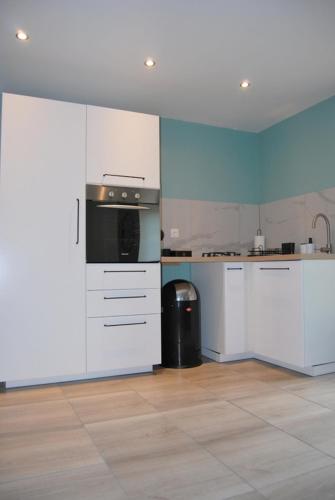 une cuisine avec des armoires blanches et un appareil noir dans l'établissement L'éolienne, à Valensole