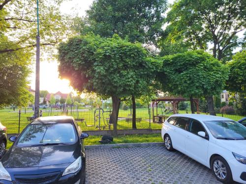 two cars parked next to a park with a playground at Apartament DeLuxe 4 in Oświęcim