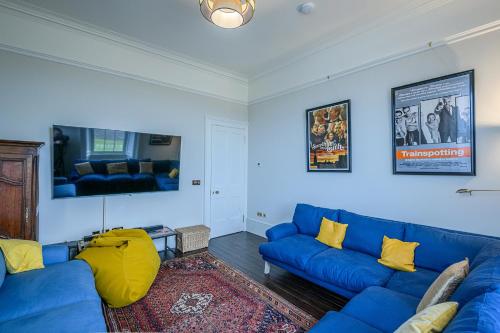 a living room with blue couches and yellow pillows at House of the Northern Gate - a luxury baronial house that sleeps 18 guests in 9 bedrooms in Thurso
