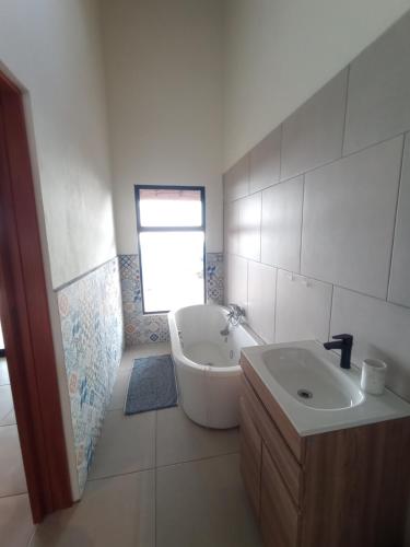 a white bathroom with a sink and a tub and a sink at VillaarcoirisCR in San Ramón