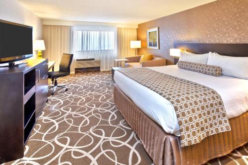 a hotel room with a bed and a flat screen tv at Crowne Plaza Kitchener-Waterloo by IHG in Kitchener