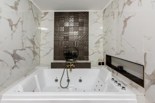 y baño con bañera blanca y paredes de mármol. en Apartament irun, en Irún