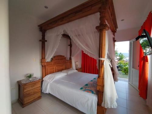 1 dormitorio con cama de madera con dosel y ventana en Finca Hotel Villa Ilusión en Pereira