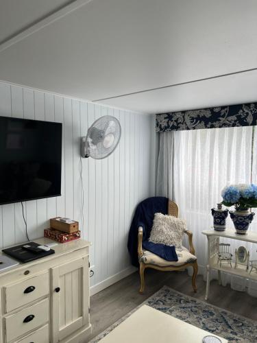 ein Wohnzimmer mit einem TV und einem Stuhl in der Unterkunft Rainbows End in Redcliffe