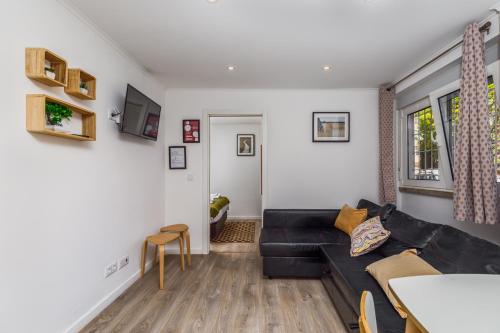 a living room with a black couch and a table at Mia Guest House Cave in Setúbal