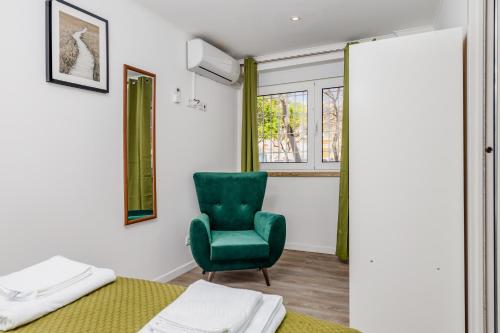 a bedroom with a green chair and a bed at Mia Guest House Cave in Setúbal