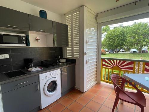 a kitchen with a washing machine and a table at FLAMBOYANT St Francois in Saint-François