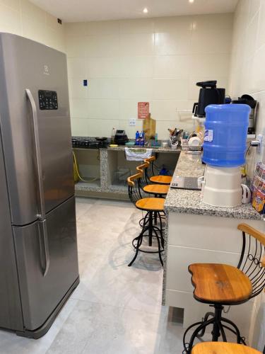 uma cozinha com um frigorífico de aço inoxidável e bancos de bar em valenshostel em Angra dos Reis