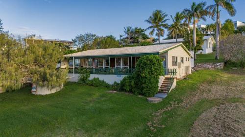 a house with a porch and a yard at Endeavour - Rustic Two-Bedroom Home With Stunning Ocean & 1770 Headland Views in Seventeen Seventy