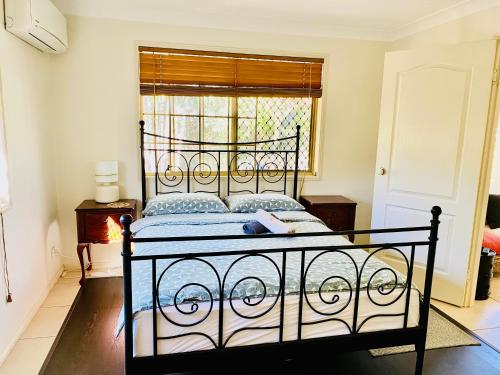 Cama negra en habitación con ventana en Granny flat en Brisbane