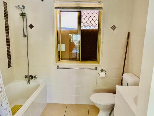 ein Bad mit einer Badewanne, einem WC und einem Fenster in der Unterkunft Granny flat in Brisbane