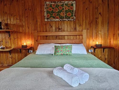 a bedroom with a bed with two white socks on it at Pousada Aconchego do Caboclo in Sapucaí-Mirim