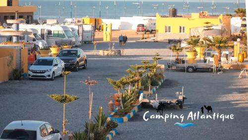 camping atlantique tan tan في Tan-Tan Plage: موقف للسيارات مع السيارات المركونه والنخيل