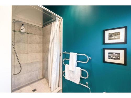 a bathroom with a shower with a blue wall at Delamore Cove - Manuka - Waiheke Escapes in Matiatia Bay