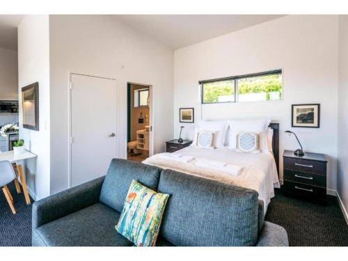 a bedroom with a bed and a couch at Delamore Cove - Manuka - Waiheke Escapes in Matiatia Bay