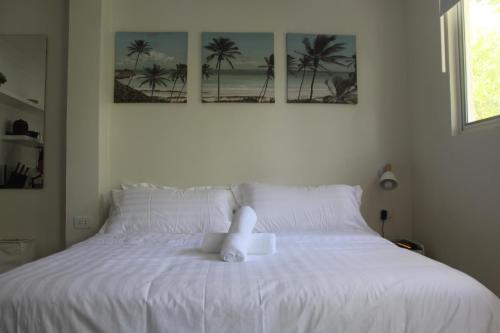 a white bed with a teddy bear sitting on it at Boracay Luxury Apartments in Boracay