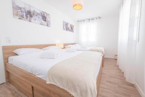 - 2 lits dans une chambre dotée de murs blancs et de parquet dans l'établissement Disneyland-Paris - 8 personnes, Wifi, Parking, à Serris