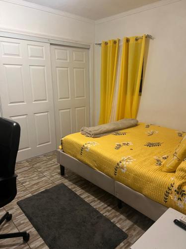 Schlafzimmer mit einem Bett mit gelben Vorhängen und einem Schreibtisch in der Unterkunft Room in Apartment - Bahamas petapat suite in Nassau