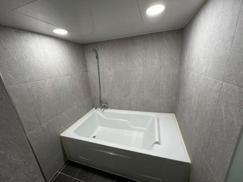 y baño con bañera y pared de azulejos. en Hotel Luna Hanok Village, en Jeonju