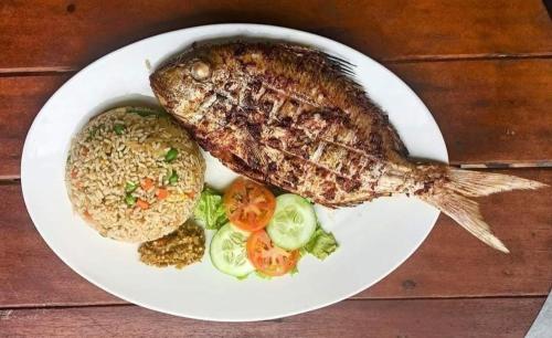 une plaque blanche de nourriture à base de poisson et de riz dans l'établissement Royal Island Breeze Resort SL, à Freetown