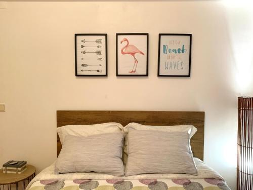 a bedroom with three pictures on the wall above a bed at Apartamento Fonte Velha in Nazaré