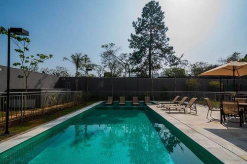 a swimming pool with tables and chairs and a fence at Apto Moderno e Acolhedor in Sao Paulo