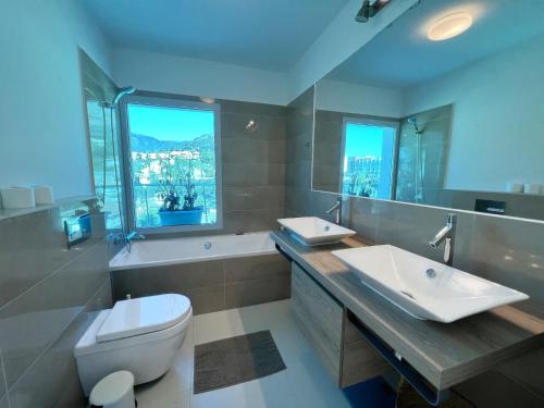 a bathroom with two sinks and a toilet and a window at Beautiful modern apartement with Jacuzzi, 1 km from the beach in Torremuelle