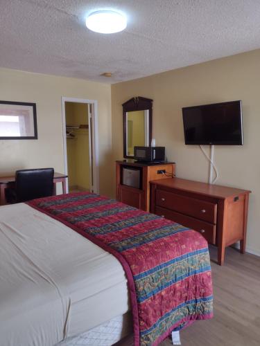 ein Hotelzimmer mit einem Bett, einem Schreibtisch und einem TV in der Unterkunft Rolling Fork Motel 