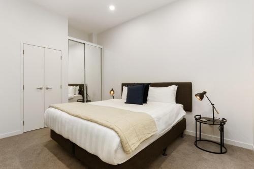 um quarto com uma cama grande e paredes brancas em Hobson Quay Apartments by Urban Rest em Auckland