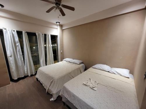 1 dormitorio con 2 camas y ventilador de techo en Restaurante y Hostal Romayor, en El Congo