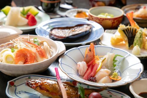una mesa con platos de comida y tazones de comida en Tsukasa Ryokan en Saga