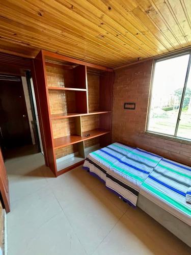 1 dormitorio con 1 cama en una habitación con ventana en El pinar, Dindalito, en Bogotá
